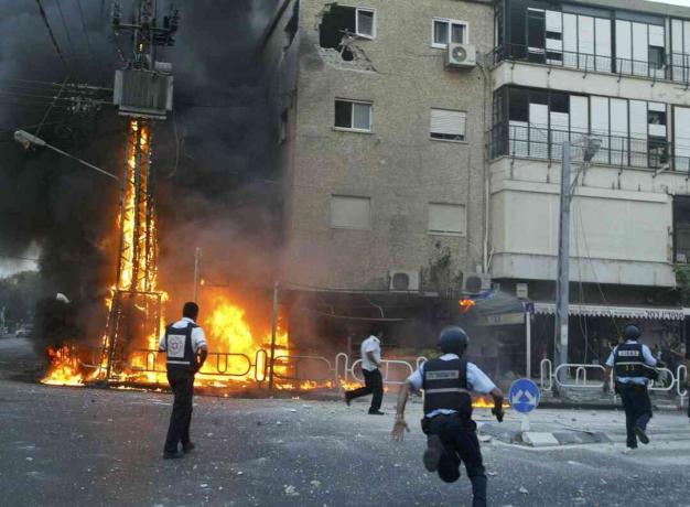 Iisraeli politseinikud kiirustavad põleva elektritorni ja kahjustatud ehitushetkede kohale pärast seda, kui 13. juulil 2006 lõi Iisraelis Nahariya linnas Hezbollah rakettide võrk.