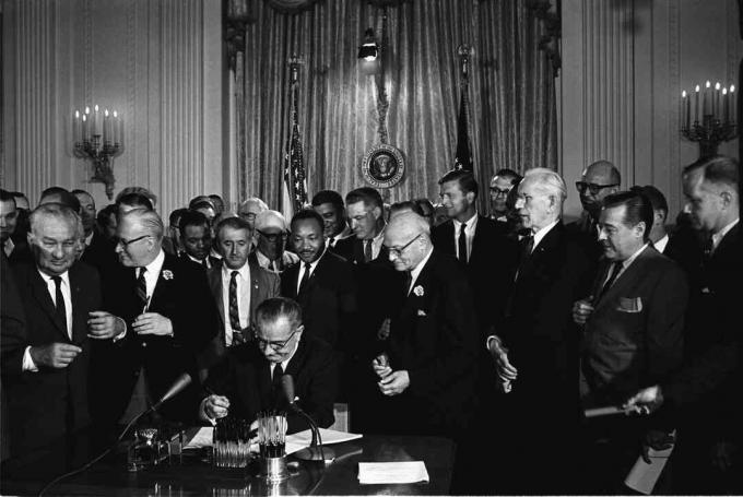 President Lyndon B. Johnson kirjutab alla 1964. aasta kodanikuõiguste seadusele, kui Martin Luther King Jr ja teised vaatavad.